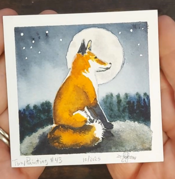A small painting of a fox sitting on a rock with a full moon in the background, surrounded by dark trees and a starry sky. The fox is depicted in vibrant orange and gold tones, with metallic watercolor effects enhancing the moon's glow.